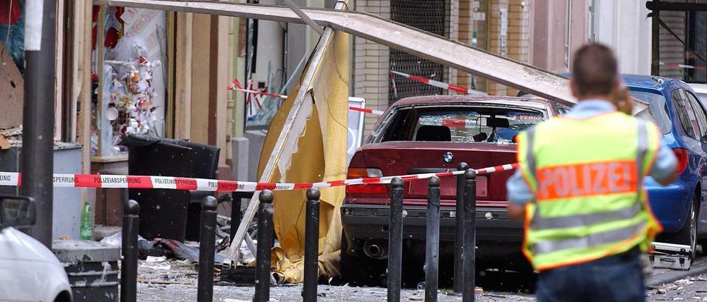 Ein Polizist sichert in der Kölner Keupstraße die Spuren der Explosion im Juni 2004. 