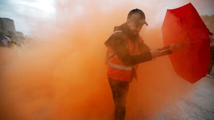 Beim Generalstreik in Frankreich schützt sich ein Demonstrant mit einem Regenschirm vor Rauch.