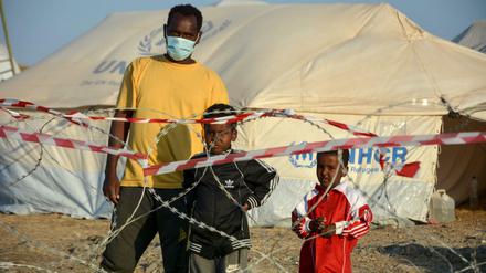 Ein Migrant steht mit zwei Kindern vor einem Stacheldrahtzaun im neu errichteten temporären Flüchtlingslager in Kara Tepe. 