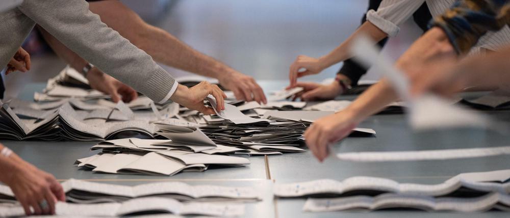 Wahlhelfer und Wahlhelferinnen zählen in einem Wahllokal Stimmzettel für die Bundestagswahl und das Abgeordnetenhaus.