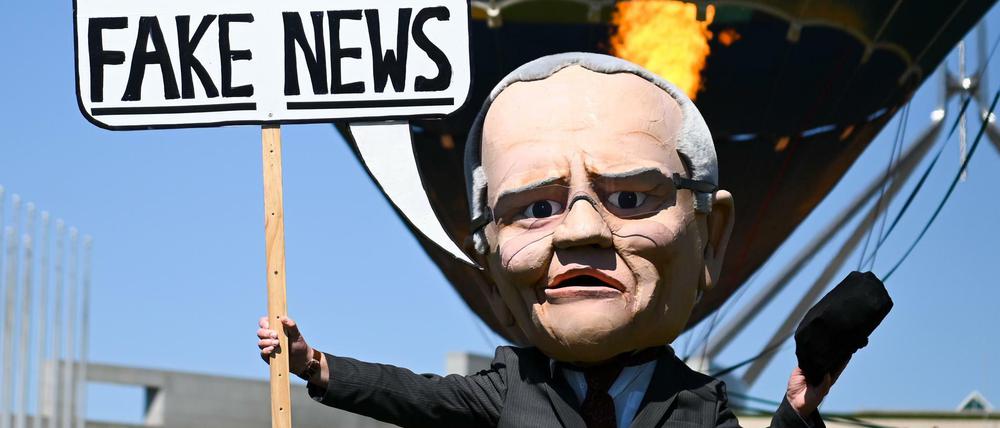 Eine Puppe, die Premier Morrison nachempfunden ist, hält ein Schild mit der Aufschrift "Klimanotstand? Fake News!"