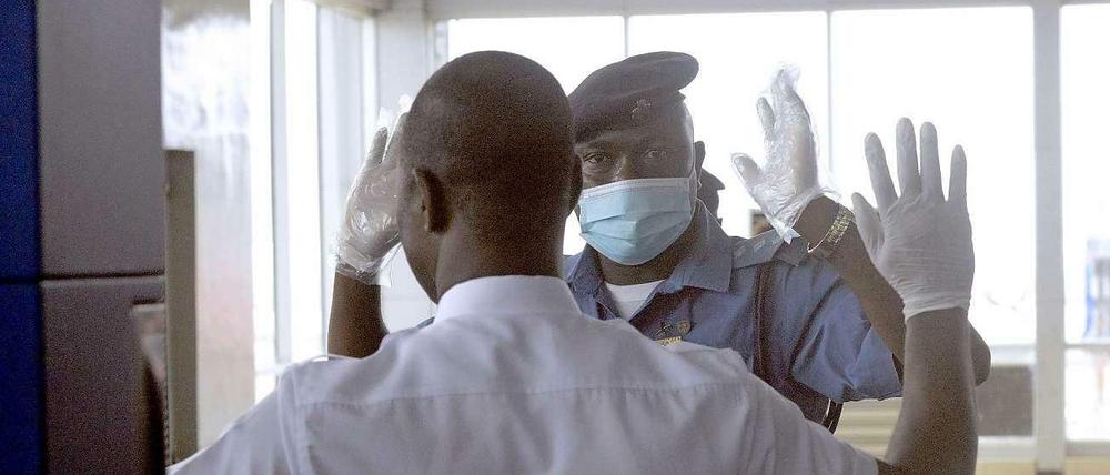 Mit Mundschutz und Handschuhen überprüft ein Mitarbeiter des Flughafens von Lagos einen Passagier.