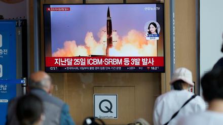 Menschen sehen einen Fernsehbildschirm, auf dem eine Nachrichtensendung über den nordkoreanischen Raketenstart gezeigt wird.