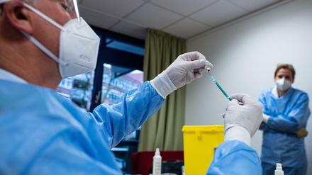 Ein Infektiologe zieht in einem Seniorenheim eine Spritze mit Impfstoff gegen das Coronavirus auf. 