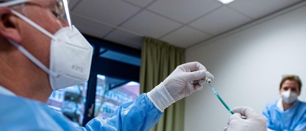 Ein Infektiologe zieht in einem Seniorenheim eine Spritze mit Impfstoff gegen das Coronavirus auf. 