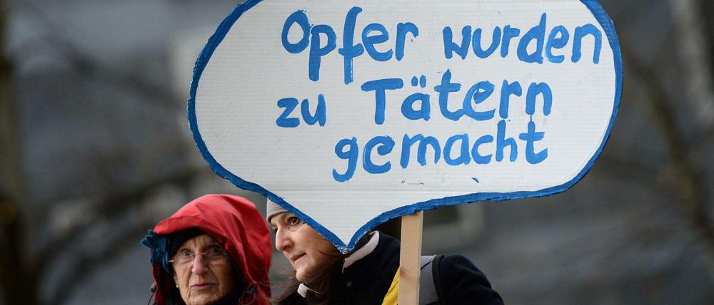 Mitglieder der Initiative «Keupstraße ist überall» stehen vor dem Oberlandesgericht in München und halten ein Schild mit der Aufschrift «Opfer wurden zu Tätern gemacht» in die Höhe.