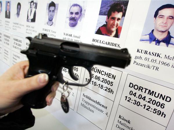 Eine mit der Mordwaffe baugleiche Pistole vor Bildern der NSU-Opfer
