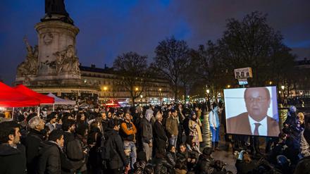 Teilnehmer der "Nuit debout"-Kundgebung verfolgen auf dem Pariser Platz der Republik das TV-Interview von Präsident Hollande.
