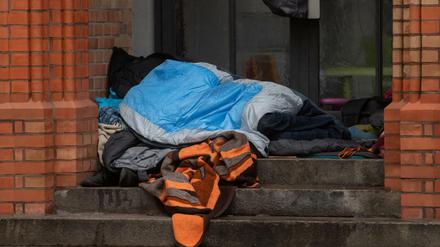 Ein Obdachloser liegt unter einer Decke in einem Eingang einer Kirche in Kreuzberg. 