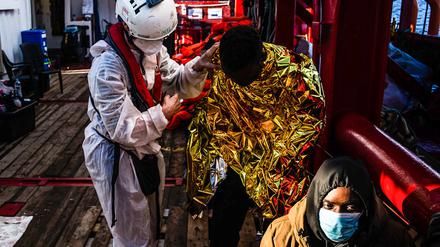 Ein Mitarbeiter des Seenotrettungsschiffs „Ocean Viking“ versorgt gerettete Migranten.