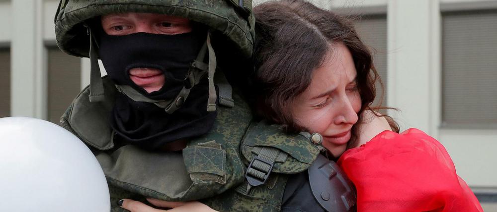 Eine Frau umarmt einen Soldaten vor dem Regierungsgebäude in Minsk. 
