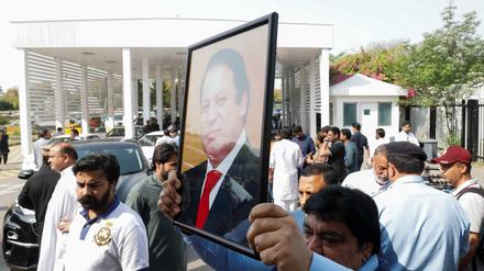 Ein pakistanischer Abgeordneter hält vor dem Misstrauensvotum ein Bild des Premier Khan in die Luft. 