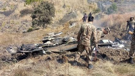 Pakistanische Soldaten untersuchen die Wrackteile eines indischen Kampfjets.