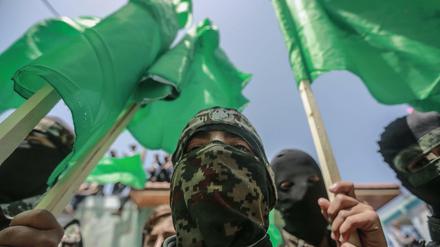 Maskierte Anhänger der palästinensischen islamistischen Hamas-Bewegung schwenken Fahnen bei einer Demonstration.