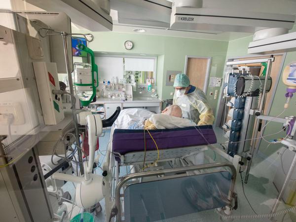 Ein Arzt untersucht in Schutzkleidung einen Corona-Patienten auf der Intensivstation im bayerischen Gauting.