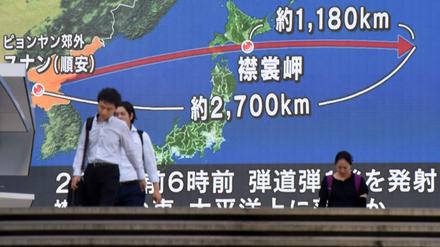 Passanten gehen in Tokio an einem TV-Screen vorbei, der die Laufbahn einer nordkoreanischen Rakete zeigt.