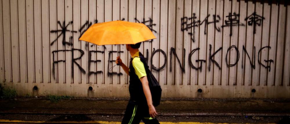 Ein Mann mit Regenschirm läuft in Hongkong. 
