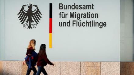 Menschen gehen an einem Bürogebäude des Bundesamtes für Migration und Flüchtlinge (BAMF) in Berlin vorbei.