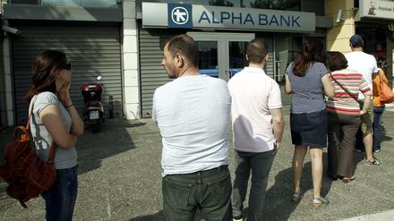 Der Bank-Run hat begonnen. Menschen stehen in Athen vor einem Geldautomaten Schlange, um noch Euro-Bargeld abheben zu können.