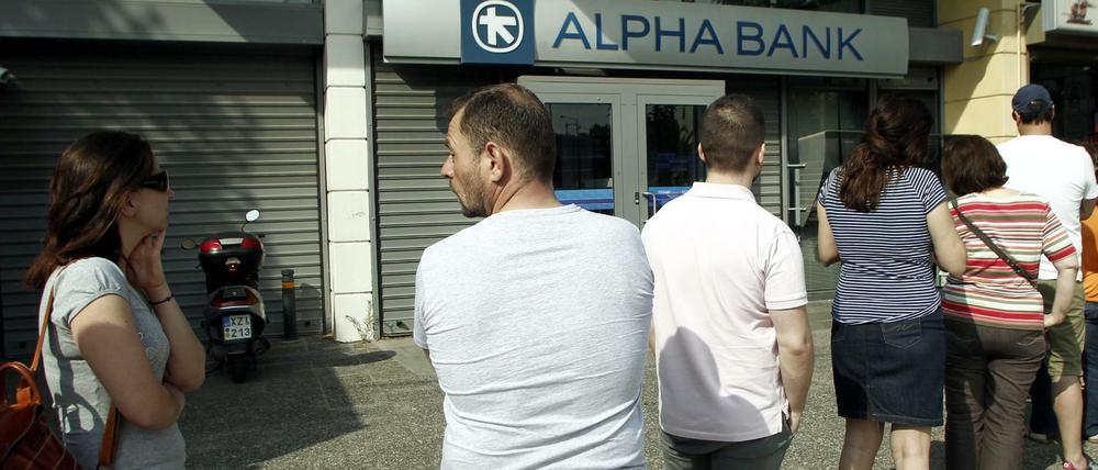Der Bank-Run hat begonnen. Menschen stehen in Athen vor einem Geldautomaten Schlange, um noch Euro-Bargeld abheben zu können.