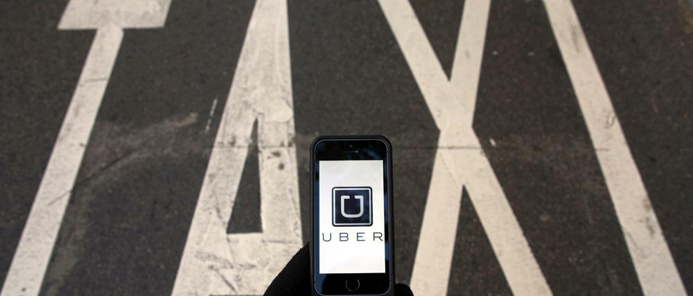 Das Logo von Uber auf einem Smartphone vor einer Taxi-Spur.
