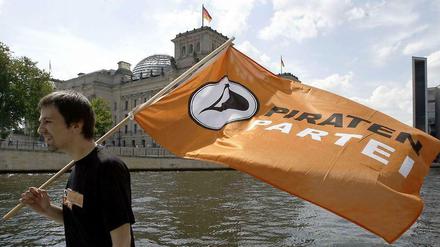 Ein Mitglied der Piratenpartei läuft mit Fahne am Ufer vor dem Berliner Reichstagsgebäude