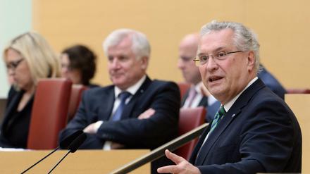 Der bayerische Innenminister Joachim Herrmann (r) spricht am 08.12.2015 bei einer Plenarsitzung im Bayerischen Landtag in München (Bayern), während im Hintergrund der bayerische Ministerpräsident Horst Seehofer (beide CSU) sitzt und zuhört. 