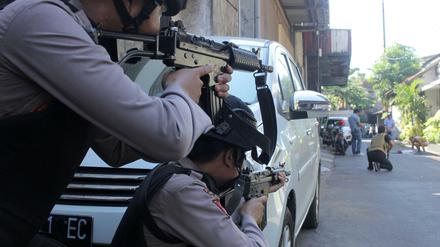 Indonesische Polizisten zielen auf einen Verdächtigen, der nach der Explosion in der Polizeizentrale von Surabaya durchsucht wird.. 