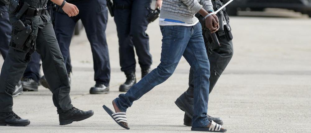 In der Landeserstaufnahmeeinrichtung für Flüchtlinge (LEA) in Ellwangen wird ein gefesselter Mann von maskierten Polizisten abgeführt. 