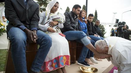Papst Franziskus küsst die Füße eines Flüchtlings. 