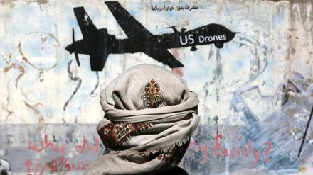Ein Jemenit steht vor einem Graffiti, mit dem gegen US-Drohnenoperationen protestiert wird. 