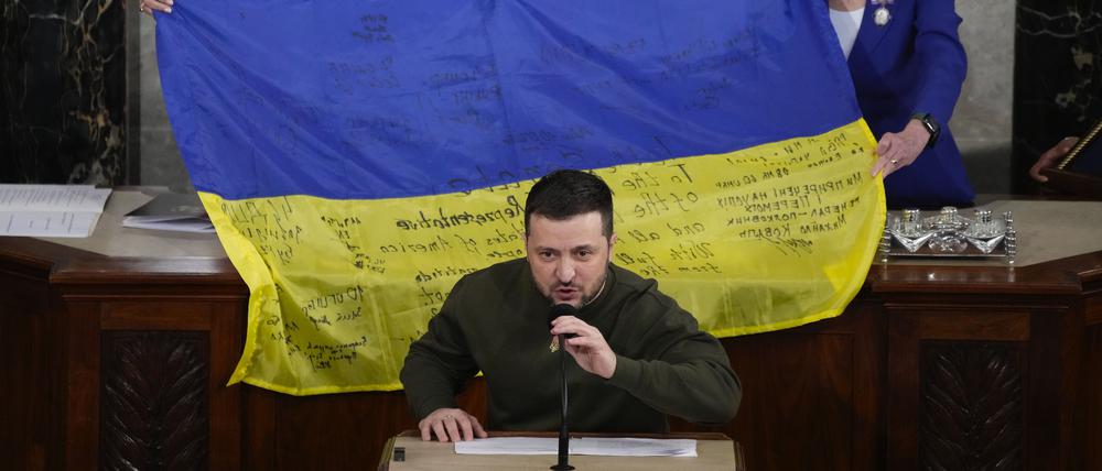 Wolodymyr Selenskyj, Präsident der Ukraine, spricht vor einer überreichten ukrainischen Flagge, die von den Frontsoldaten in Bachmut signiert wurde.