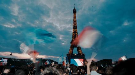 Anhänger des französischen Präsidenten Emmanuel Macron feiern am Eiffelturm mit Landesflaggen. 