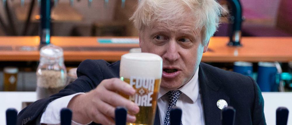 Boris Johnson, Premierminister von Großbritannien, hält bei einem Besuch in der Fourpure-Brauerei ein Bier in der Hand.