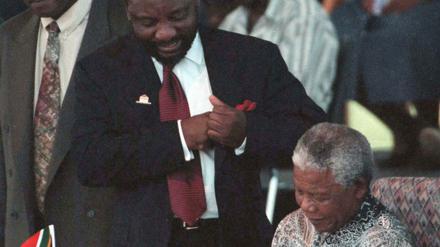 Nelson Mandela leistet die Unterschrift zur neuen Verfassung Südafrikas 1996. Cyril Ramaphosa (Mitte) schaut zu.