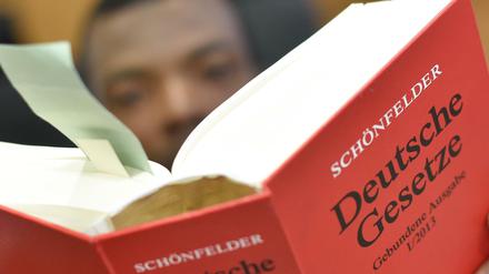 Ein Flüchtling aus Somalia hält eine Ausgabe "Schönfelder Deutsche Gesetze" in Händen.