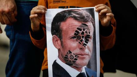 Ein Kind hält ein mit einem Schuhabdruck versehenes Foto des französischen Staatschefs Emmanuel Macron in Istanbul in die Kamera.