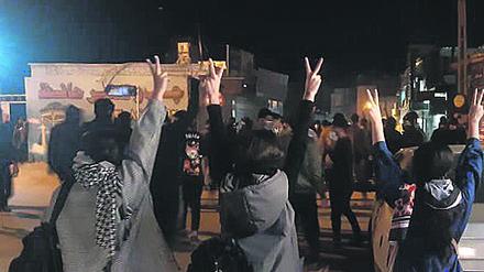 Protestierende Frauen ohne das vorgeschriebene Kopftuch heben ihre Hände und zeigen das Victory-Zeichen.