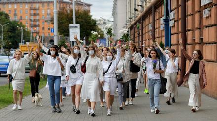 Demonstrantinnen in weißer Kleidung machen in Minsk Peace-Zeichen.