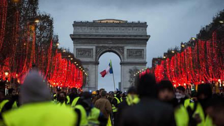Demonstranten stehen vor dem Triumphbogen in Paris