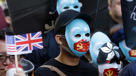 Demonstranten In Hongkong tragen Masken, auf denen eine rote Hand mit chinesischer Flagge ihnen den Mund zuhält. 