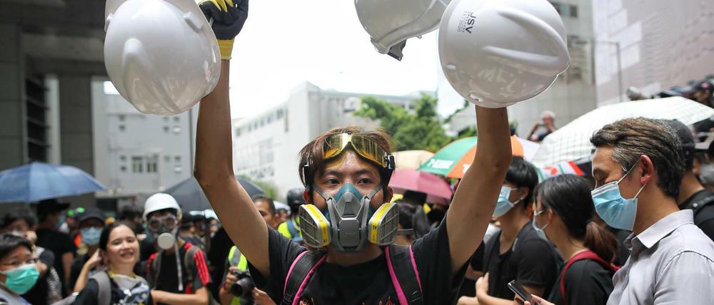 Hongkong: Ein Demonstrant mit einer Gasmaske verteilt Schutzhelme an andere Demonstranten. 