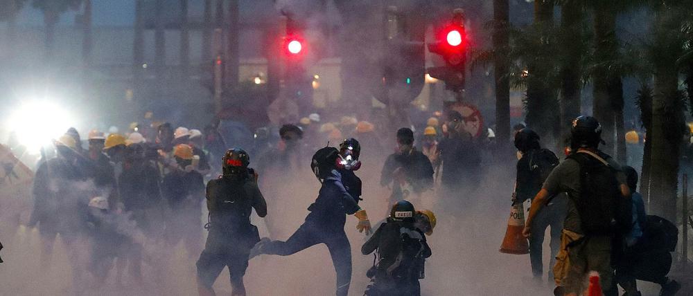 Ein Demonstrant mit einer Gasmaske wirft bei einer Straßenblockade einen Tränengasbehälter, der von der Polizei bei erneuten Unruhen eingesetzt wurde. 