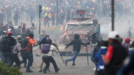 Demonstranten in Quito greifen ein Polizeifahrzeug an. 
