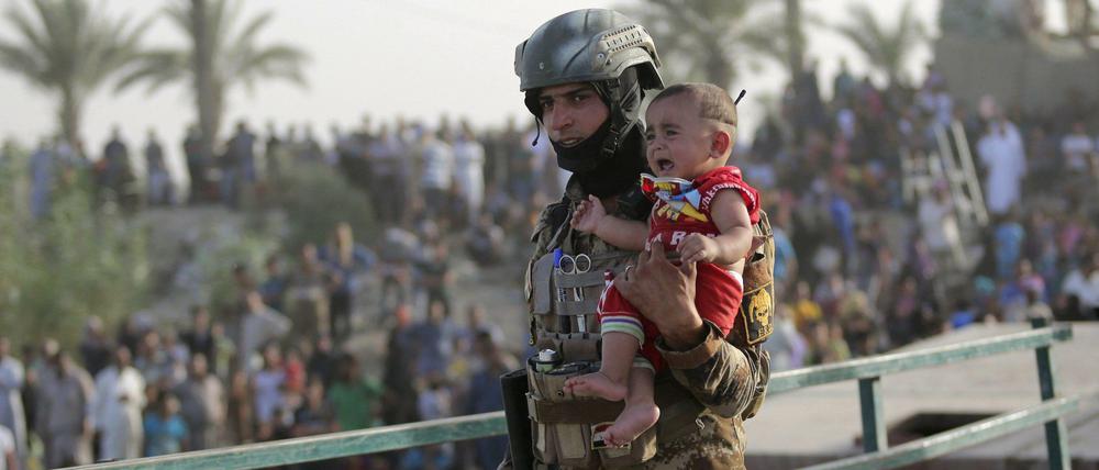 Ein irakischer Soldat bringt ein Kind in Ramadi in Sicherheit.
