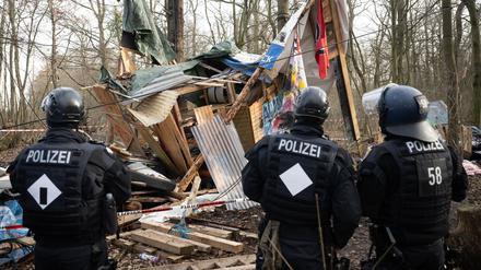 Polizeibeamte stehen während der Räumung des Gebietes im Fechenheimer Wald vor einem zerstörten Baumhaus.