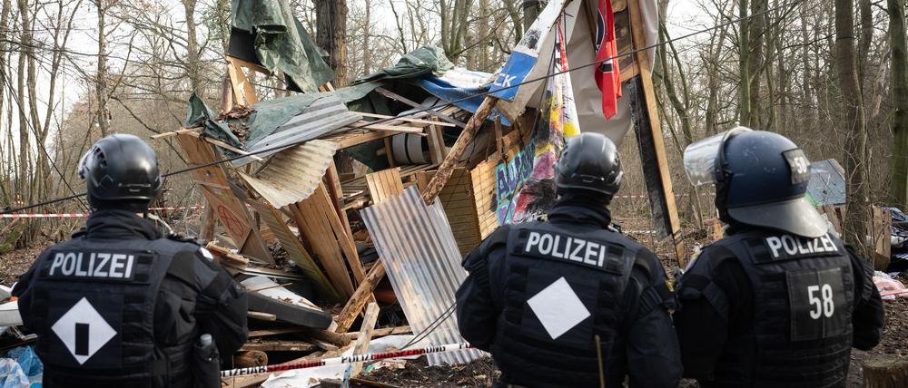 Polizeibeamte stehen während der Räumung des Gebietes im Fechenheimer Wald vor einem zerstörten Baumhaus.