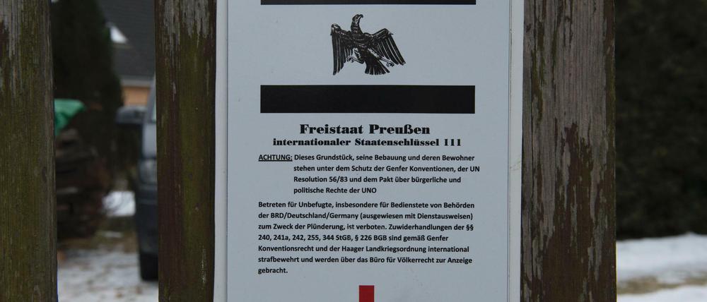 Ein Schild hängt am Grundstückstor vor dem Haus in Cottbus, in dem sogenannte Reichsbürger wohnen. Bei einer Razzia gegen die Reichsbürger wurden in der Stadt verschiedene Räumlichkeiten durchsucht.