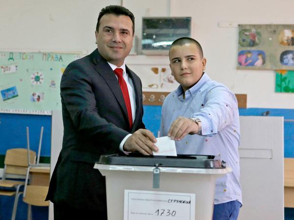 Der mazedonische Premierminister Zoran Zaev (M), begleitet von seinem Sohn Dusko, stimmt ab. 