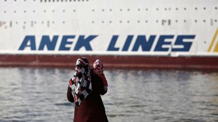 Eine geflüchtete syrische Frau blickt im Hafen von Piräus auf eine Fähre. Der Transport von Flüchtlingen soll nach dem Willen der griechischen Regierung vorerst eingeschränkt werden. 